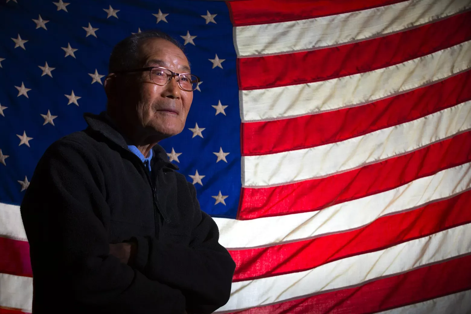 elder Japanese American man in front of American Flag